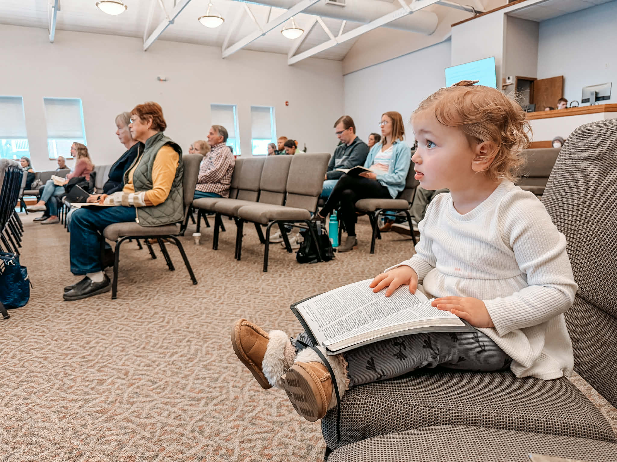 A young child sitting in the service with an open Bible on Family Sunday at Medina Community Church
